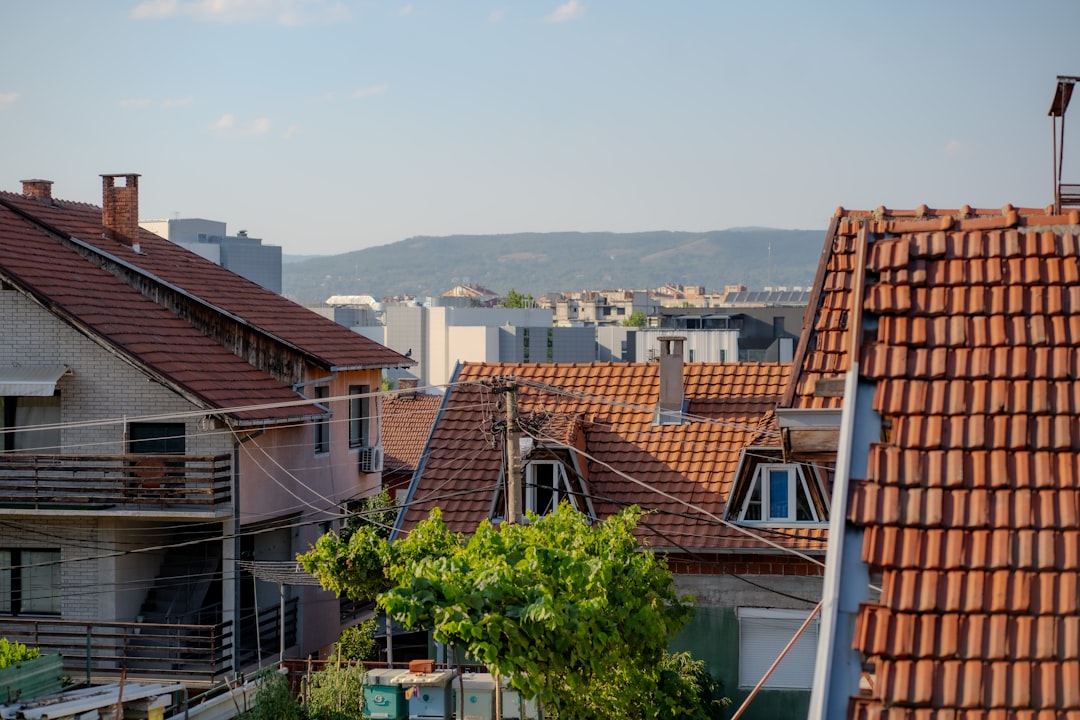 c8b8c55e1c114b2fb62c1f0791018e92 Residential houses with terracotta tiled roofs and distant mountains under a clear sky