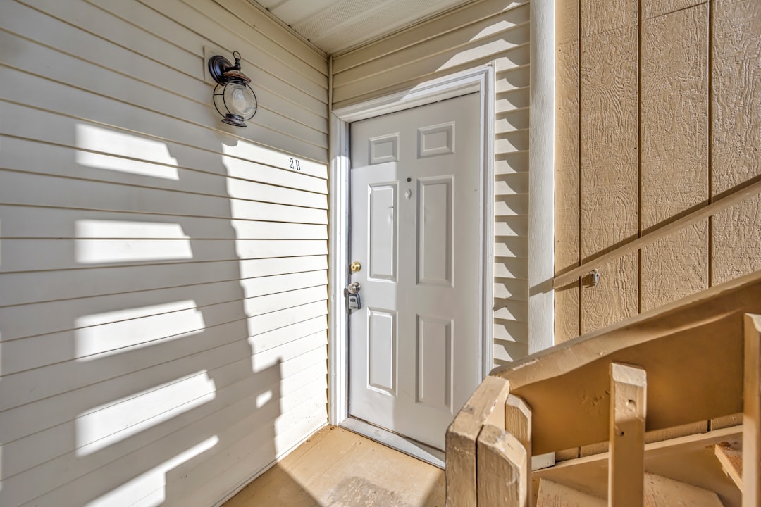 White front door with light siding and wooden railing
