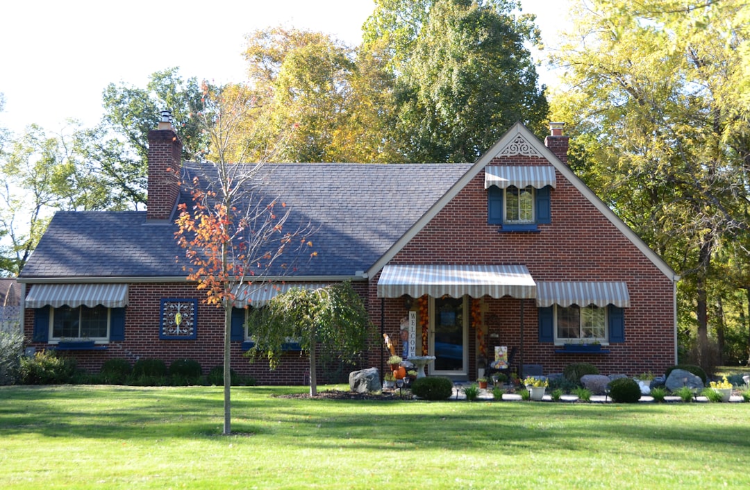 A brick house with a green lawn and trees