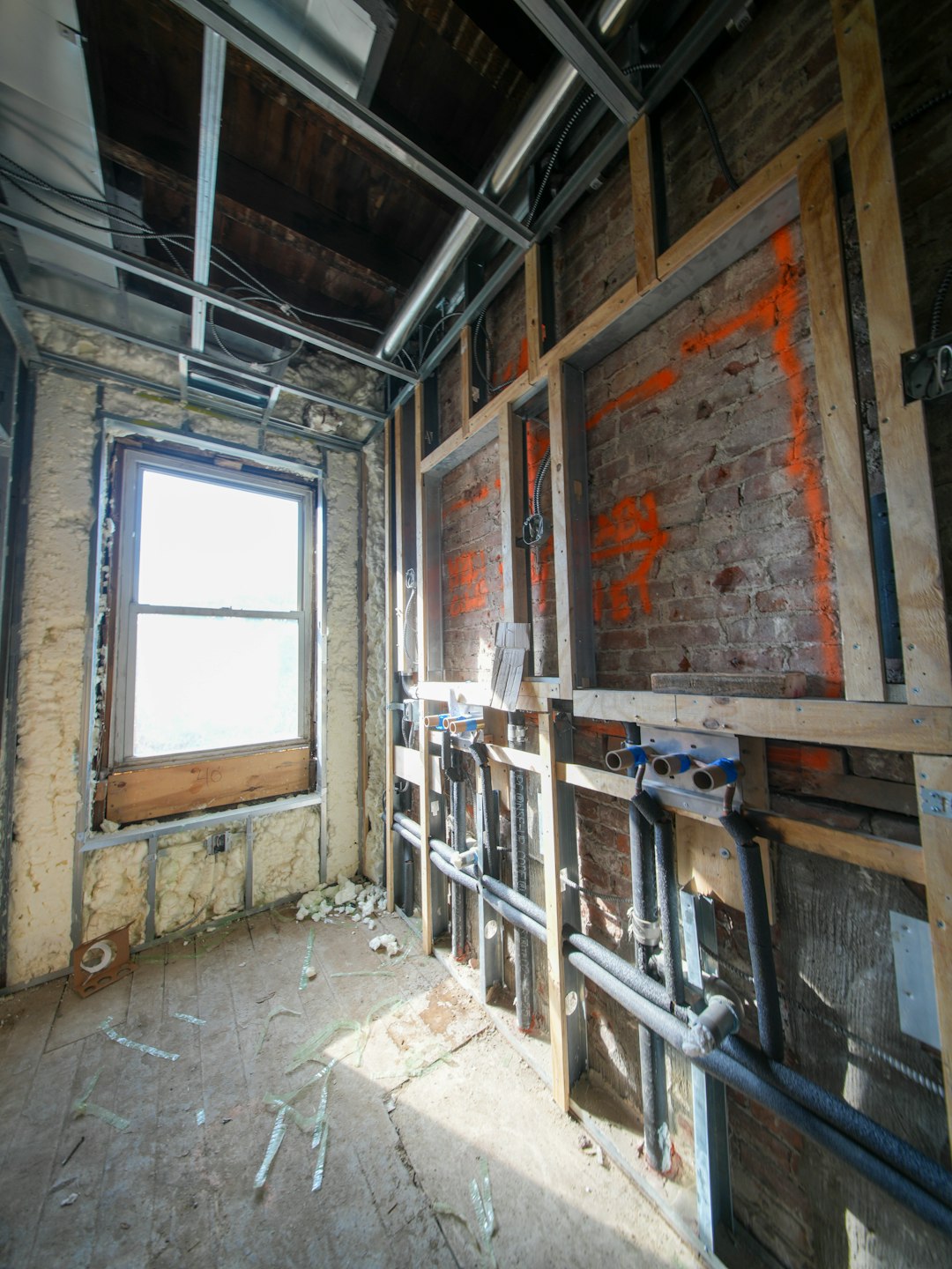 ea3b49580fd545eb9c6eb410d5c5b933 Interior under construction with exposed pipes and window