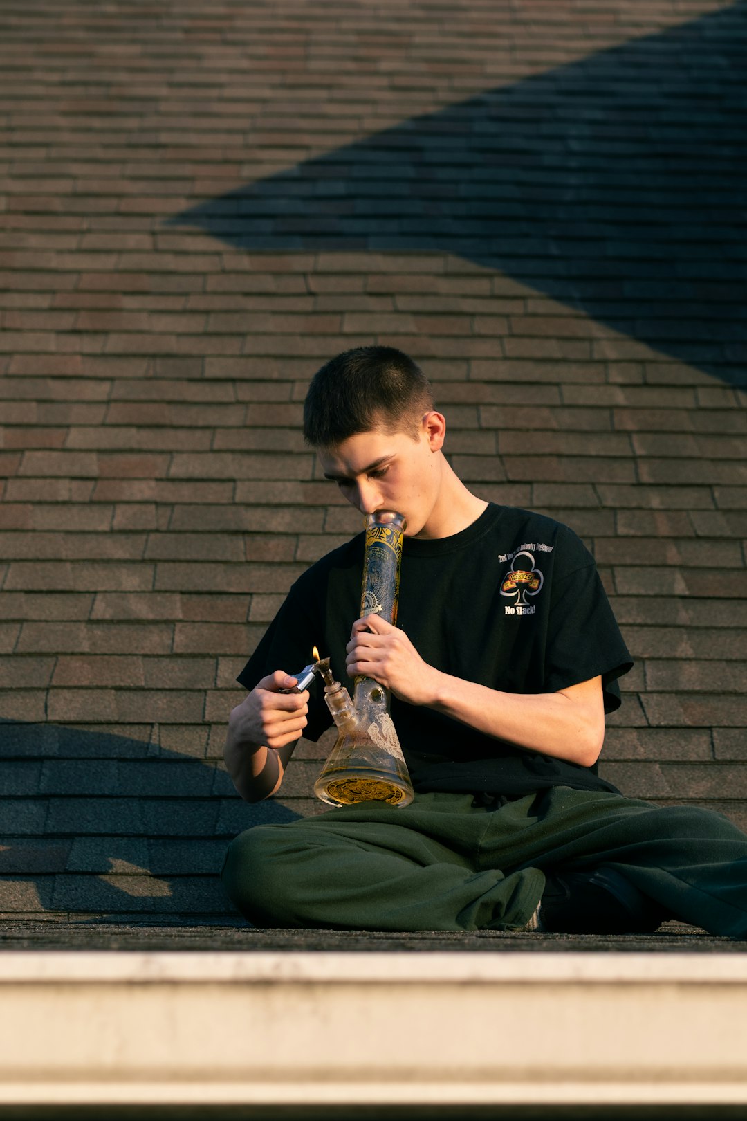 f257c7c2c7624ec0983b2a2a269dc657 Young man lighting a bong on a rooftop