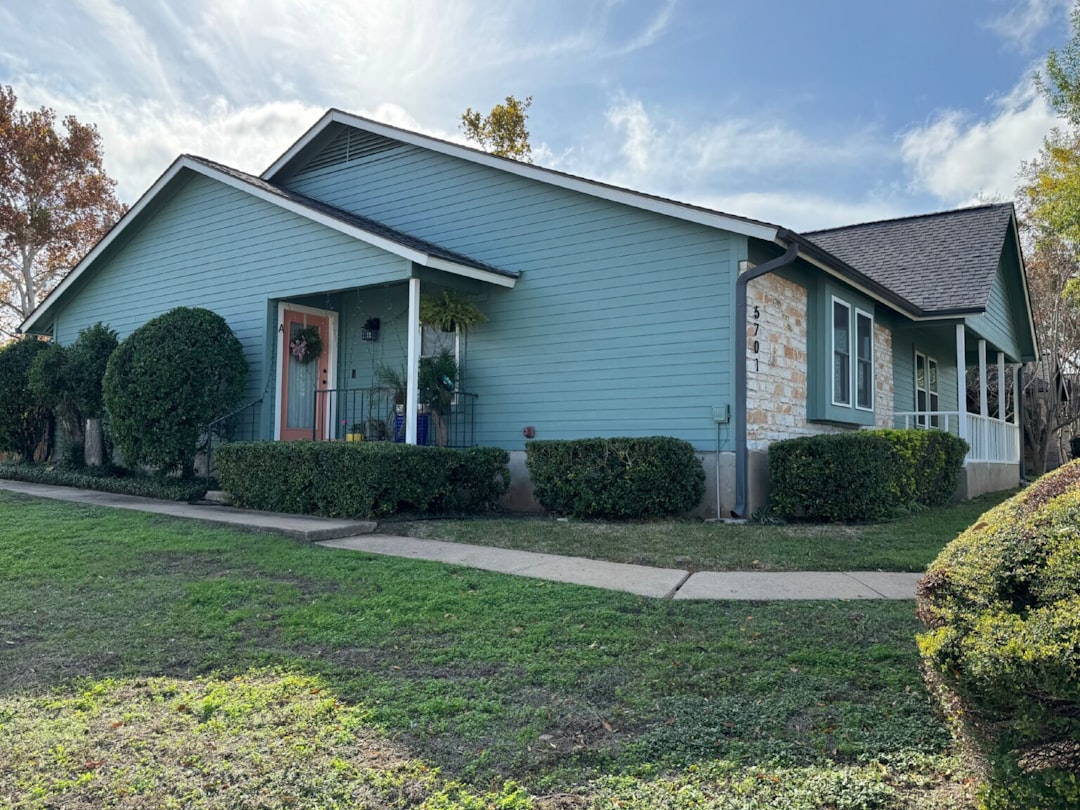 A teal house with stone accents and green lawn