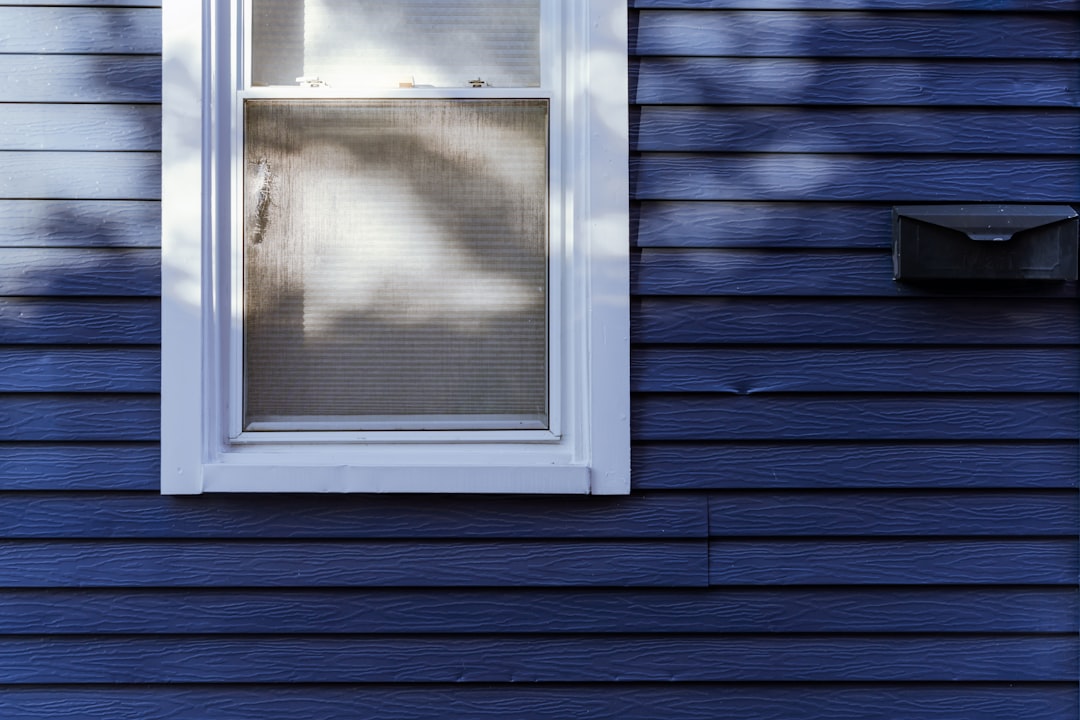 A blue house with a white window and blue siding