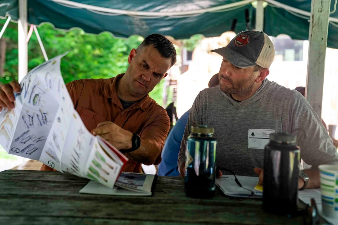 Men Reviewing Roofing Plans Two men examining a document together document outdoors