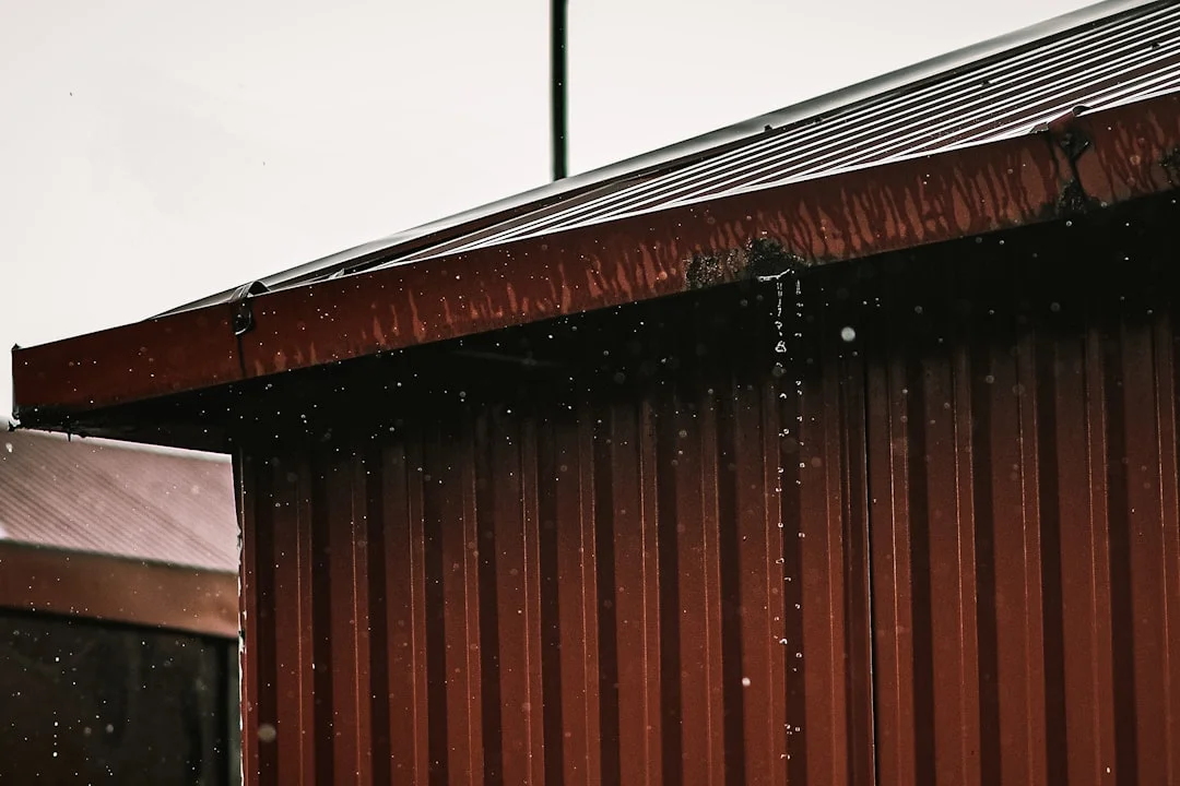 Close-Up of Metal Wall and Roof Edge a red building with snow falling on it