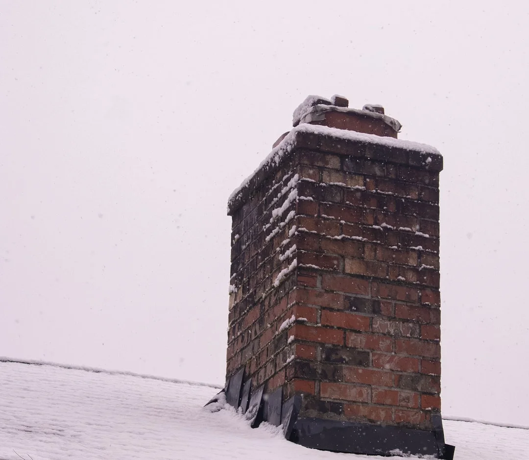 Chimney on Snow-Covered Roof A brick chimney covered in fresh snow.