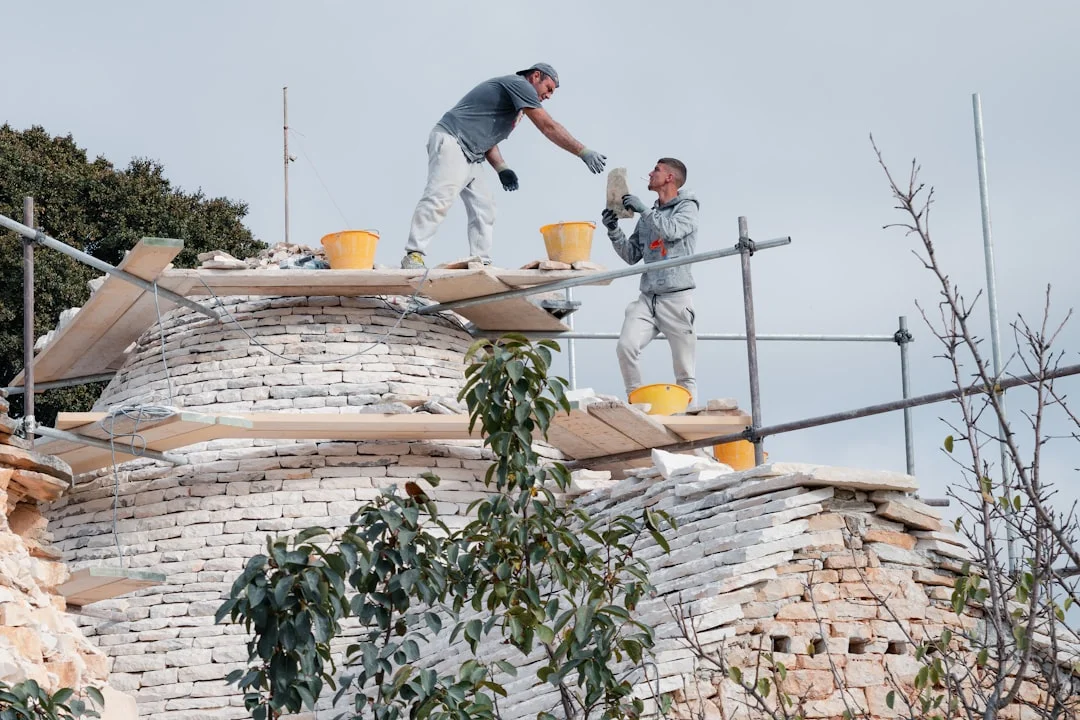 Two construction workers repairing a dome structure.