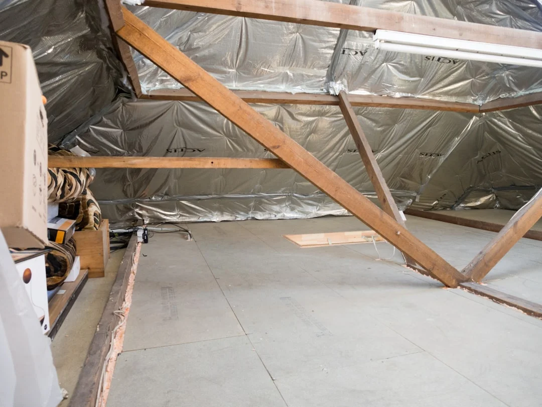 An attic with insulation and wooden beams.