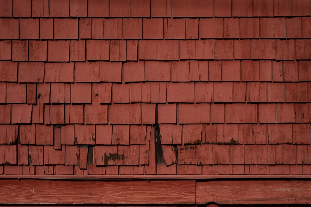 Old, weathered, red shingles cover a wall.