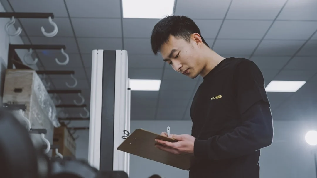 Man holding a clipboard indoors next to a metal frame