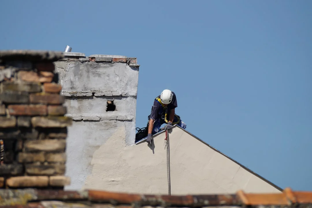 Construction Worker on Roof man in black jacket climbing on gray concrete wall during daytime