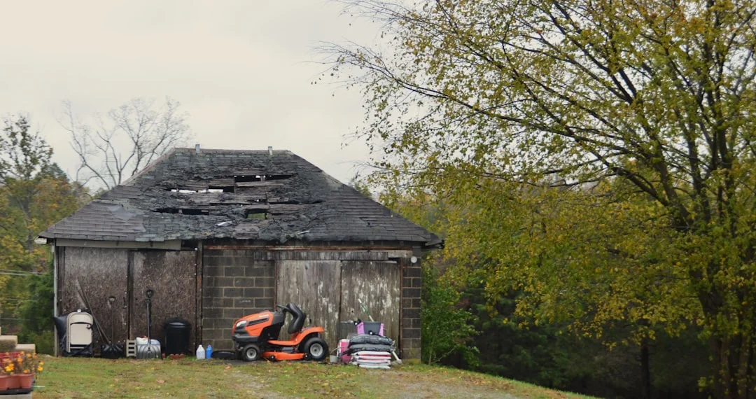 Old barn with damaged roof and lawnmower outside